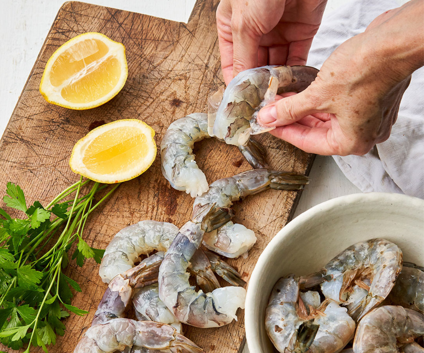 Headless shrimp being peeled surrounded by lemons