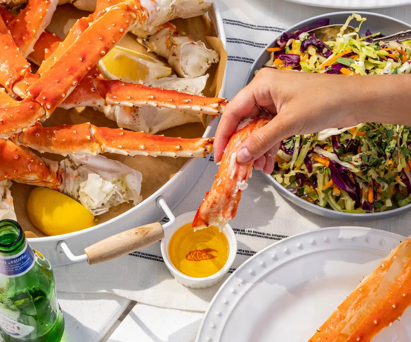 hand dipping king crab meat into a ramekin with butter