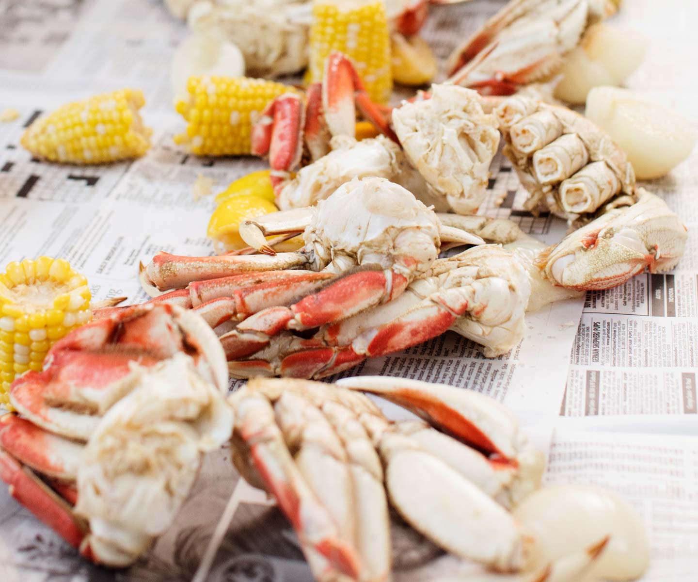 Crab legs and corn on a newspaper surface