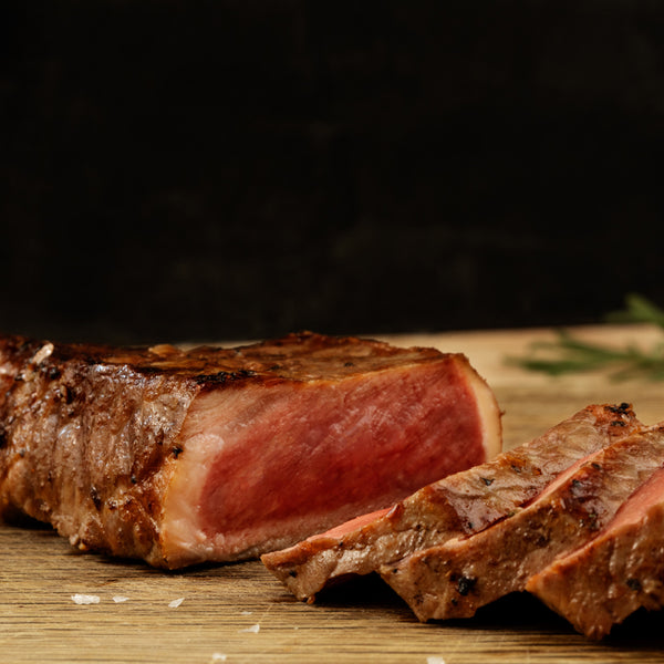 Sliced steak on a wooden cutting board with a dark background