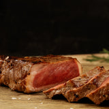 Sliced steak on a wooden cutting board with a dark background