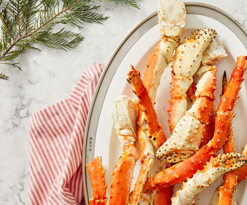 Platter of crab legs on a marble surface with a red and white striped towel.