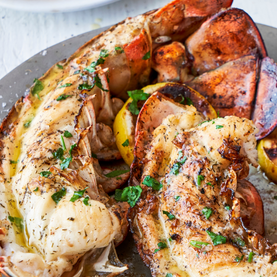 Grilled lobster tails with lemon wedges on a plate