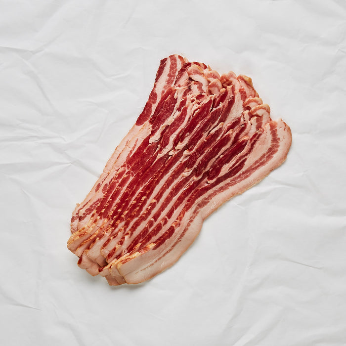 Raw bacon strip on a white quilted surface