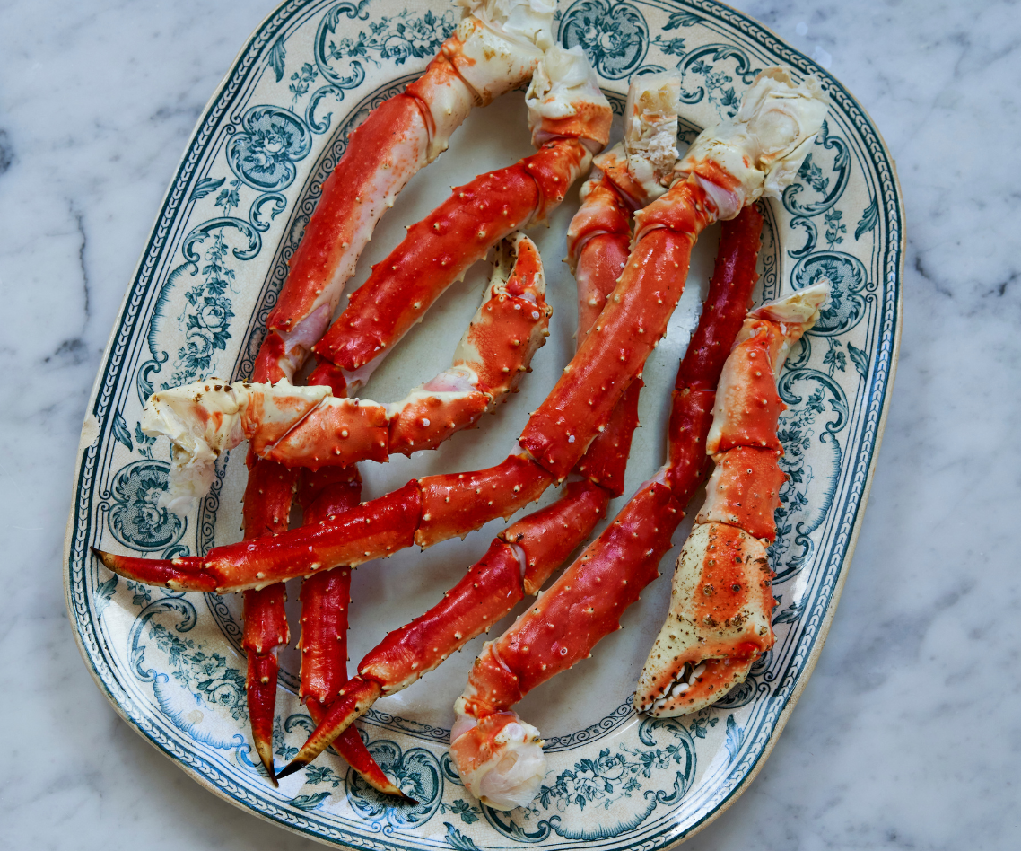 Raw crab legs on a decorative plate with a marble background