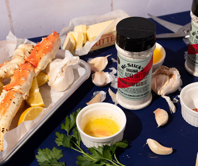 tray of crab with butter ramekin and seasoning with garlic cloves scattered about.