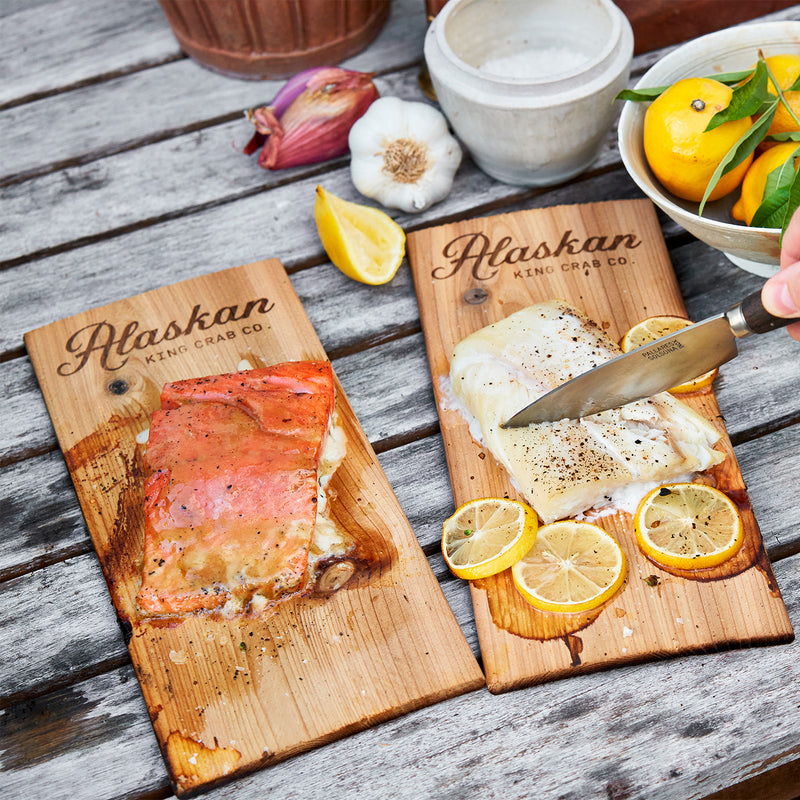 Wooden cutting boards with Alaskan King Crab Co. branding, featuring salmon and crab, on a wooden surface.