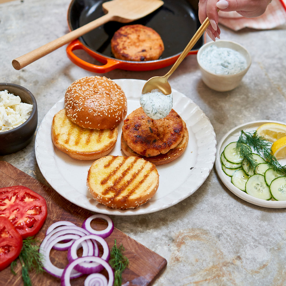 salmon burger preparation on a table with ingredients and utensils