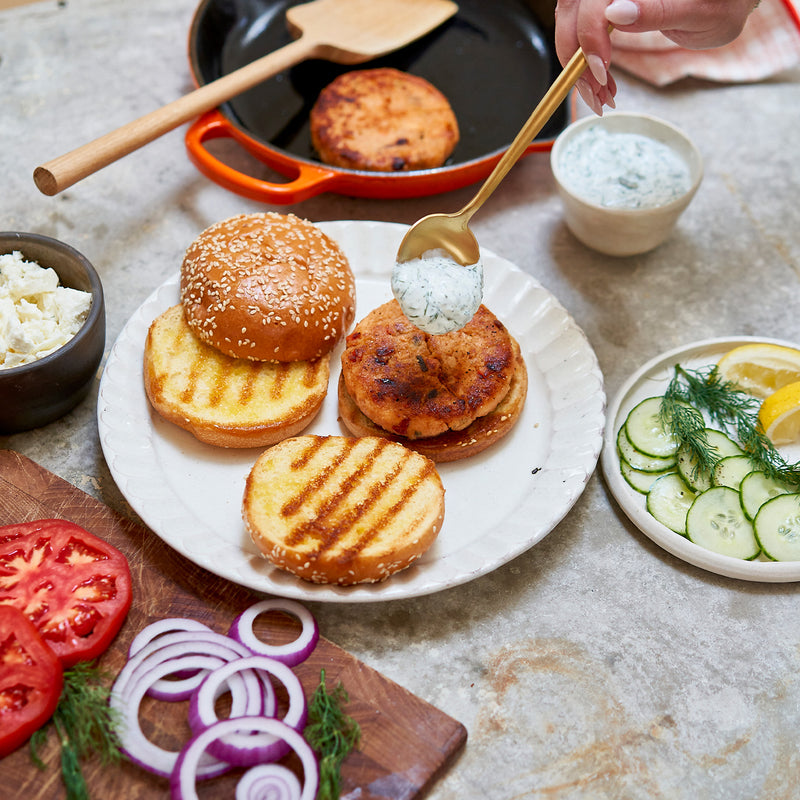 salmon burger preparation on a table with ingredients and utensils
