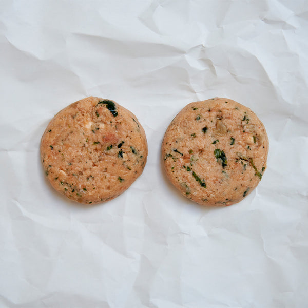 Two round salmon patties on a white fabric background