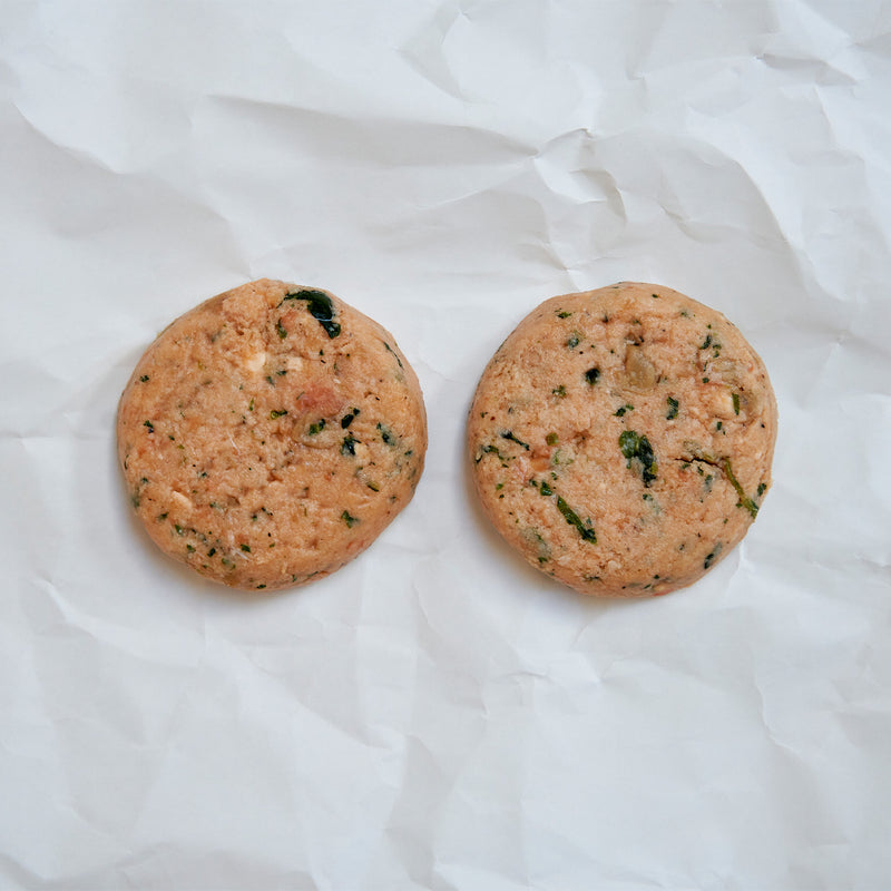 Two round salmon patties on a white fabric background
