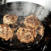 4 80/20 lean raw 1lb bricks cooking in a skillet.