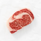 Raw Boneless Ribeye sitting against paper.