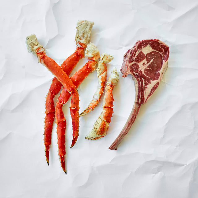 Raw crab legs and a steak on a white background