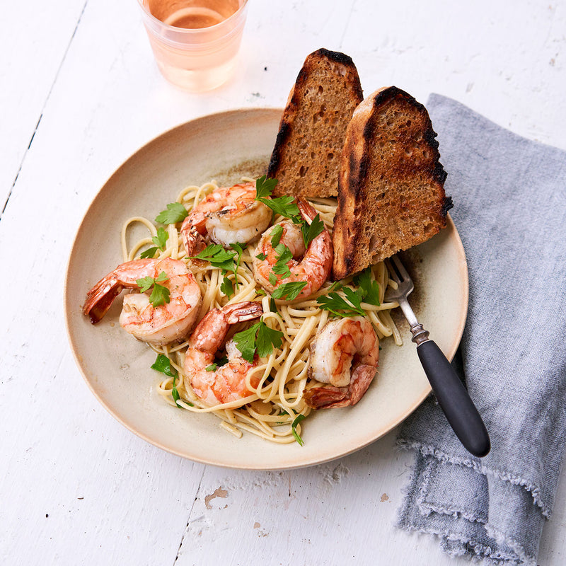 Linguine with cooked U10 White Oishii Shrimp and toasted bread in a bowl.